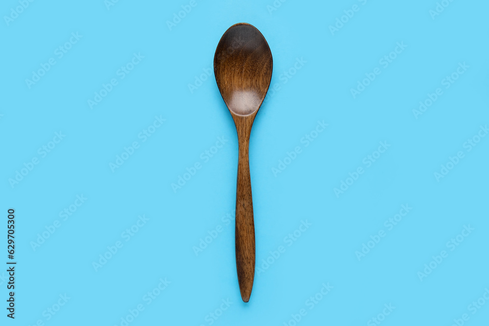 Wooden spoon on color background