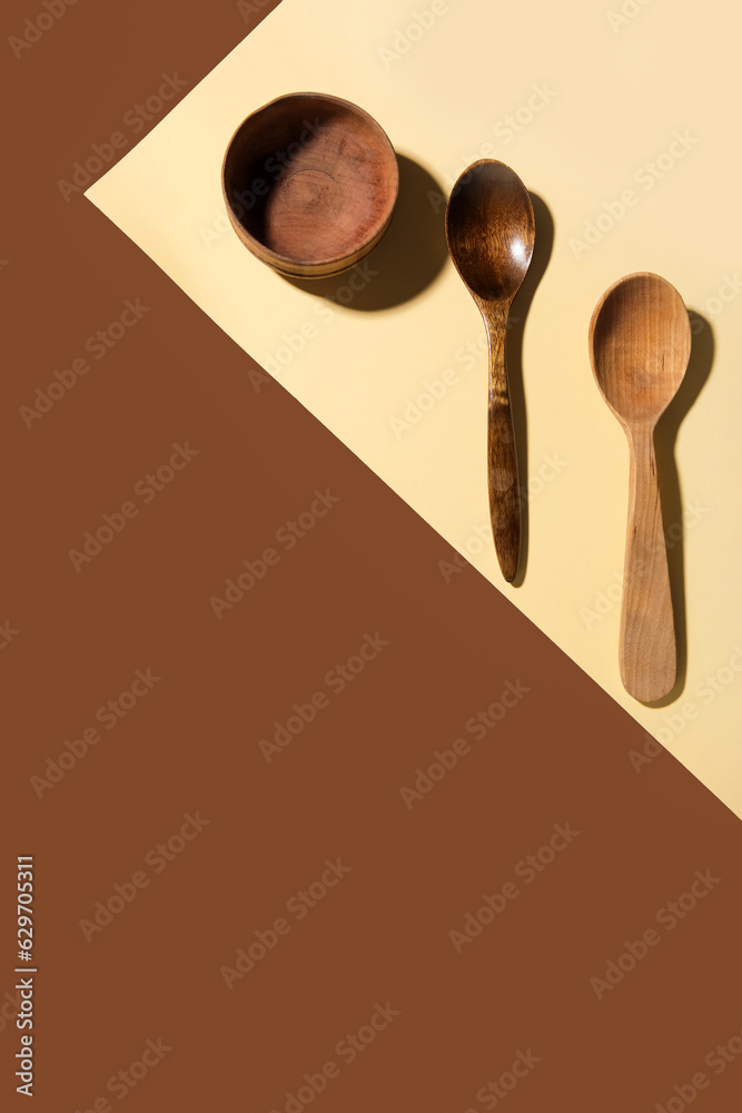 Set of wooden spoons and bowl on color background