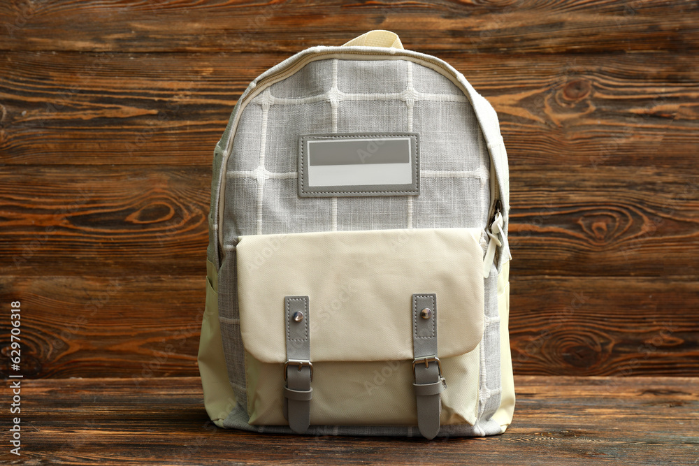 Grey school backpack on wooden background