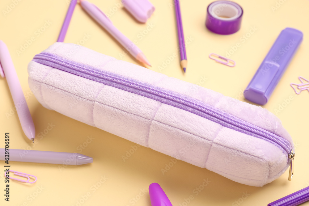 Pencil case with different stationery on yellow background