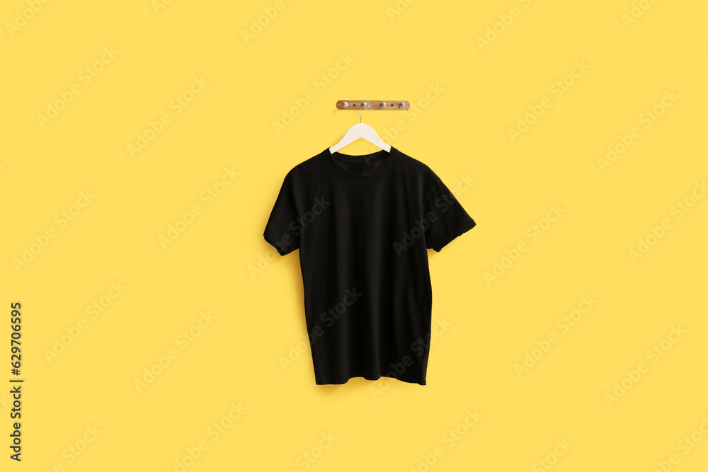 Stylish black t-shirt hanging on yellow background