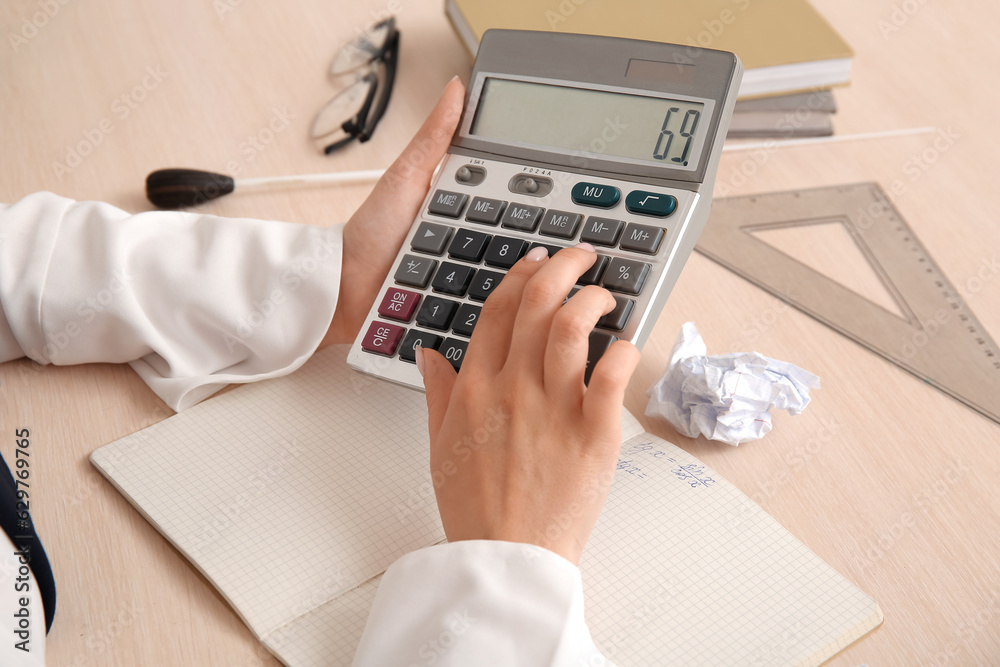 Female math teacher checking pupils homework at wooden table, closeup