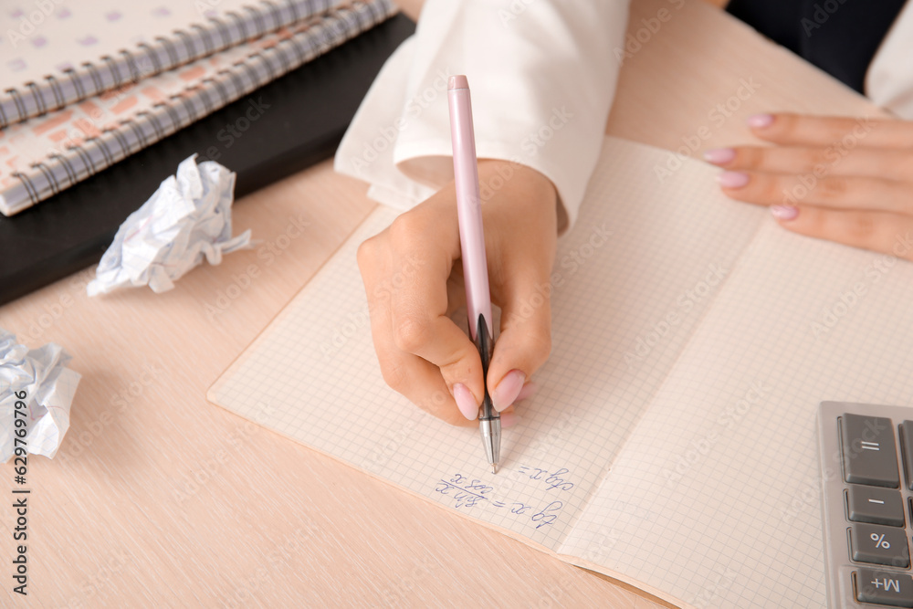 Female math teacher checking pupils homework at wooden table, closeup