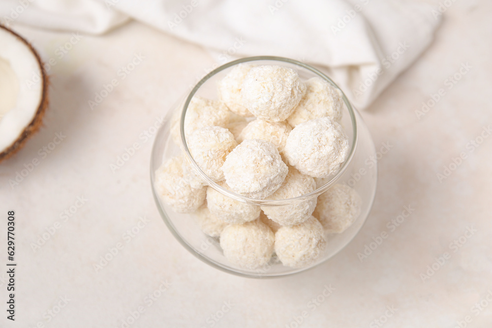 White chocolate candies with coconut topping in glass bowl on light table