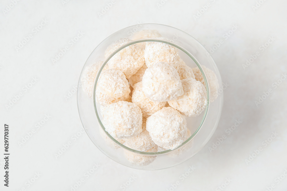 White chocolate candies with coconut topping in glass bowl on light table