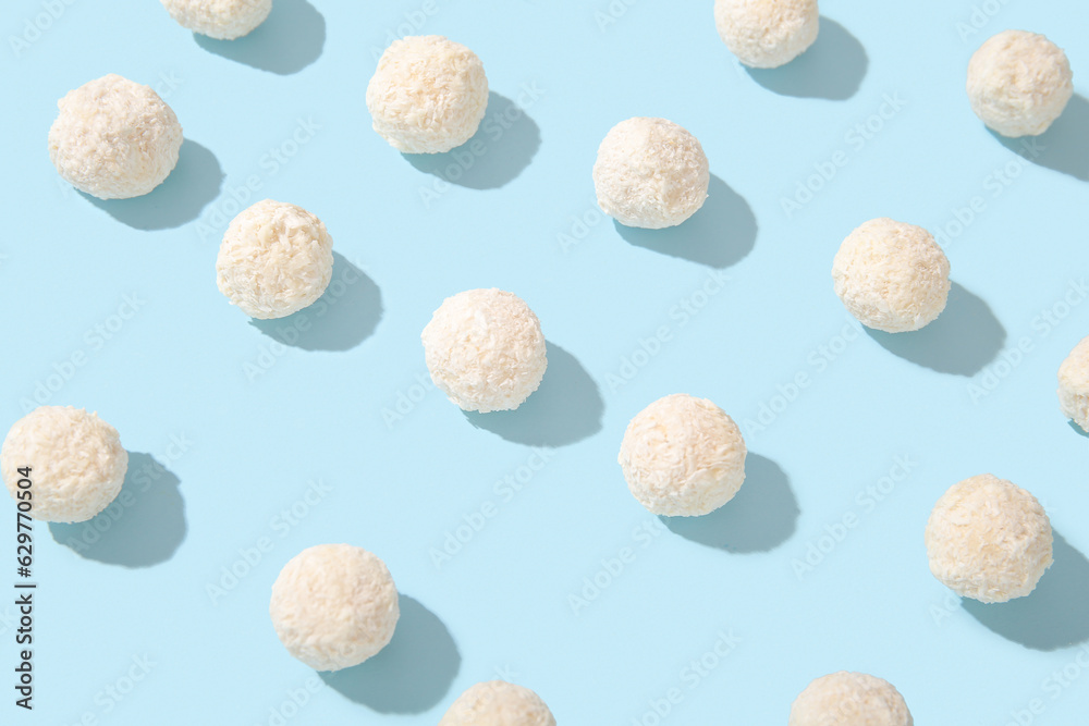 Many white chocolate candies with coconut topping on blue background