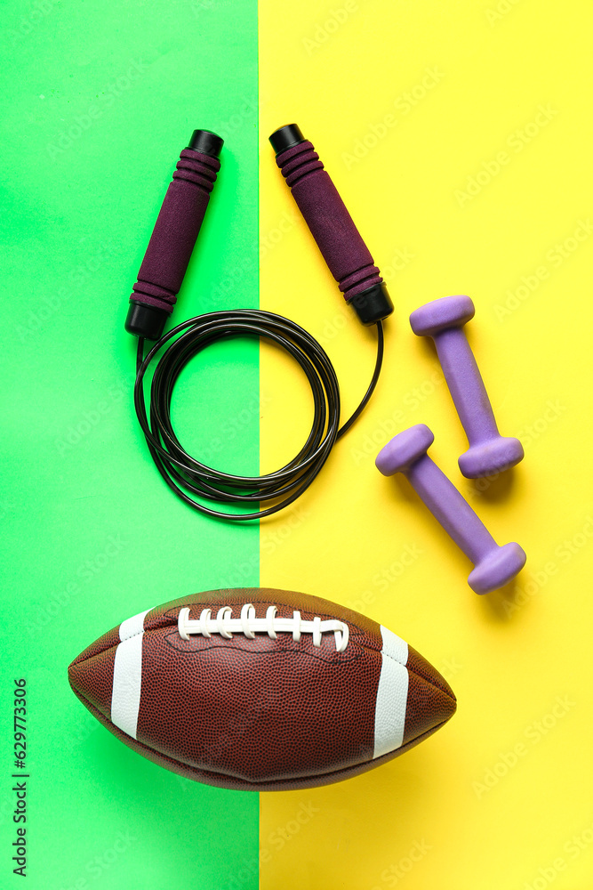 Dumbbells, skipping rope and rugby ball on color background