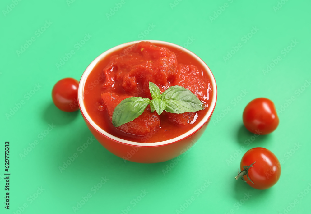 Bowl of canned tomatoes on green background