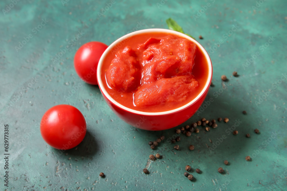 Bowl of canned tomatoes and peppercorns on color background