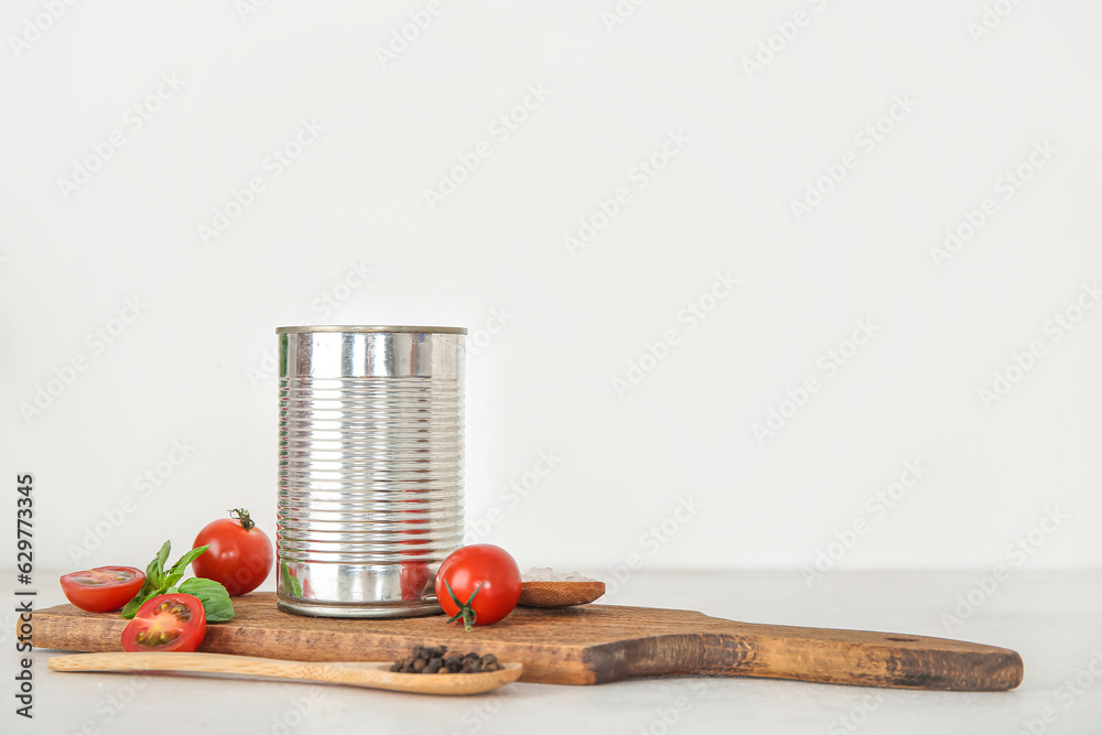 Wooden board with canned tomatoes and spices on light background