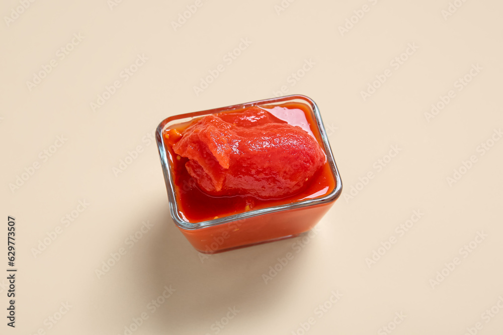 Glass bowl of canned tomatoes on color background