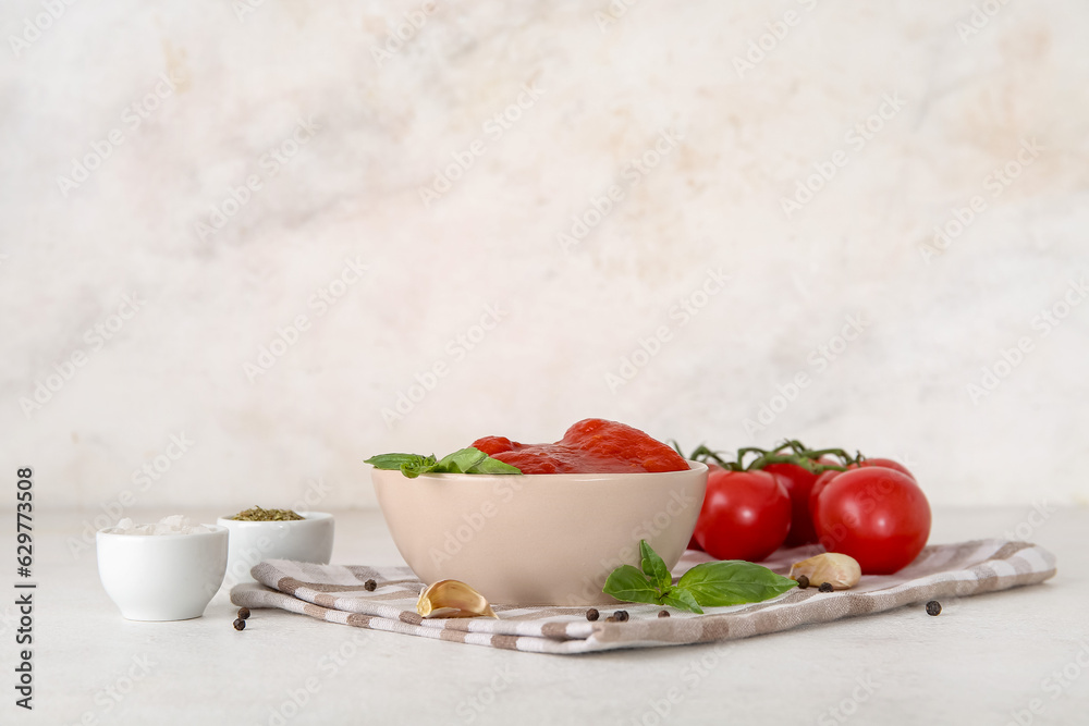 Bowl with canned tomatoes and spices on light background