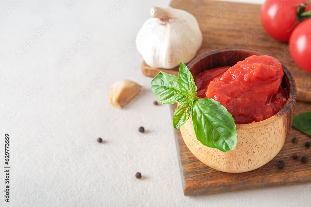 Bowl of tasty canned tomatoes and spices on light background