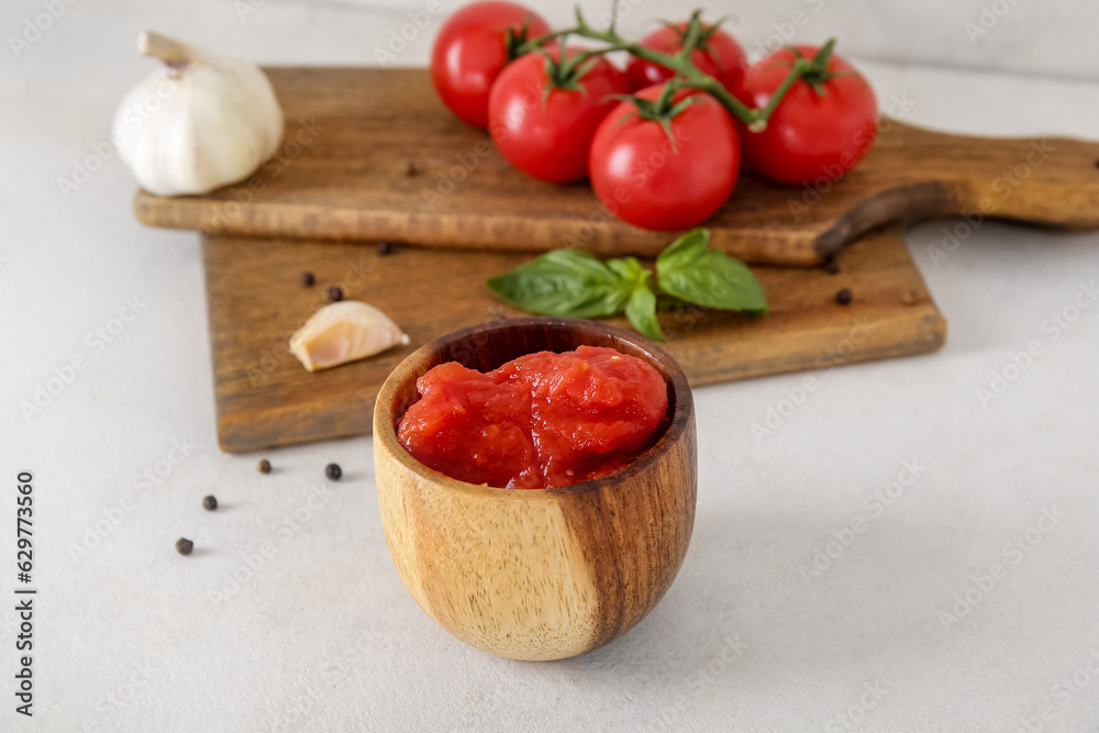 Bowl of tasty canned tomatoes and spices on light background