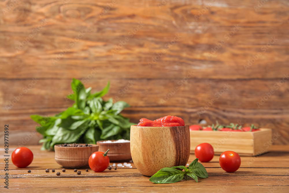 Bowl of canned tomatoes, spices and fresh basil on wooden table