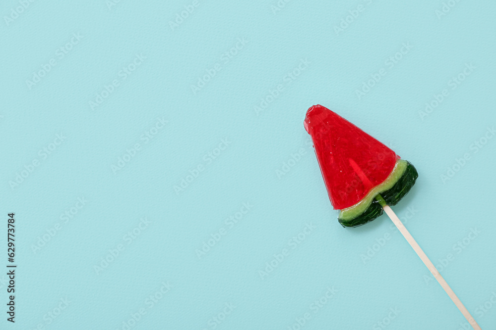 Lollipop in shape of watermelon slice on blue background