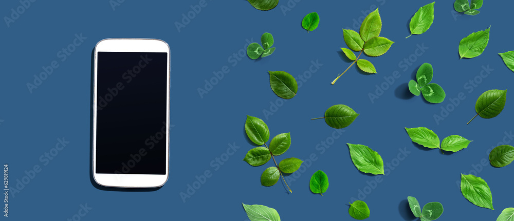 White smartphone with green leaves - flat lay