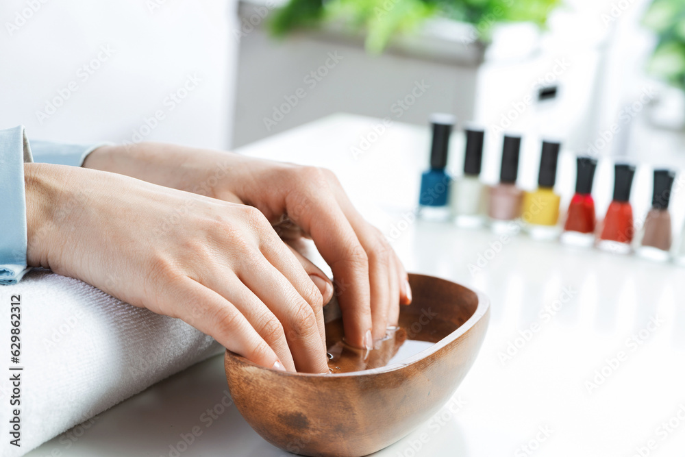 Closeup female hands in wooden bowl with water