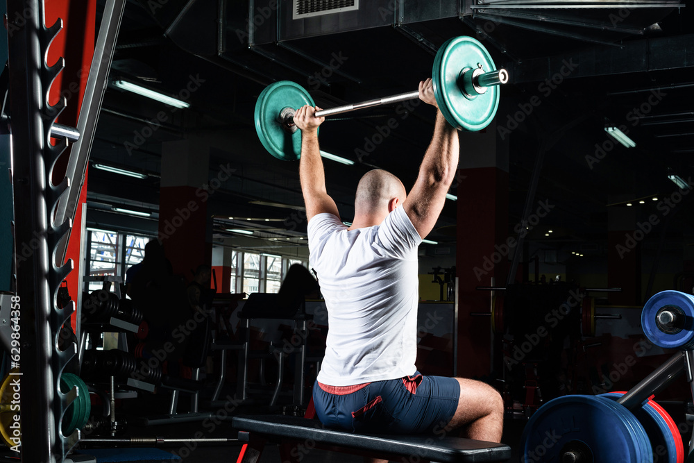 Male athlete lifts the barbell