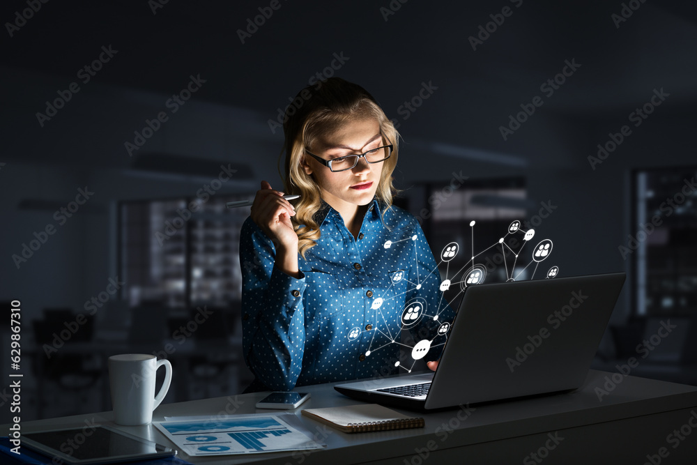 Attractive blonde wearing glasses in dark office using laptop. Mixed media