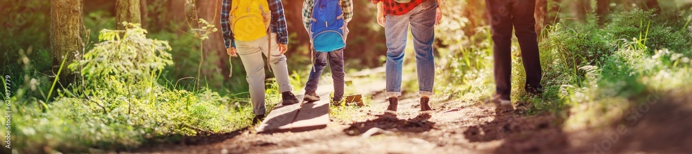 Mother and father with their sons standing in natural park with backpacks.