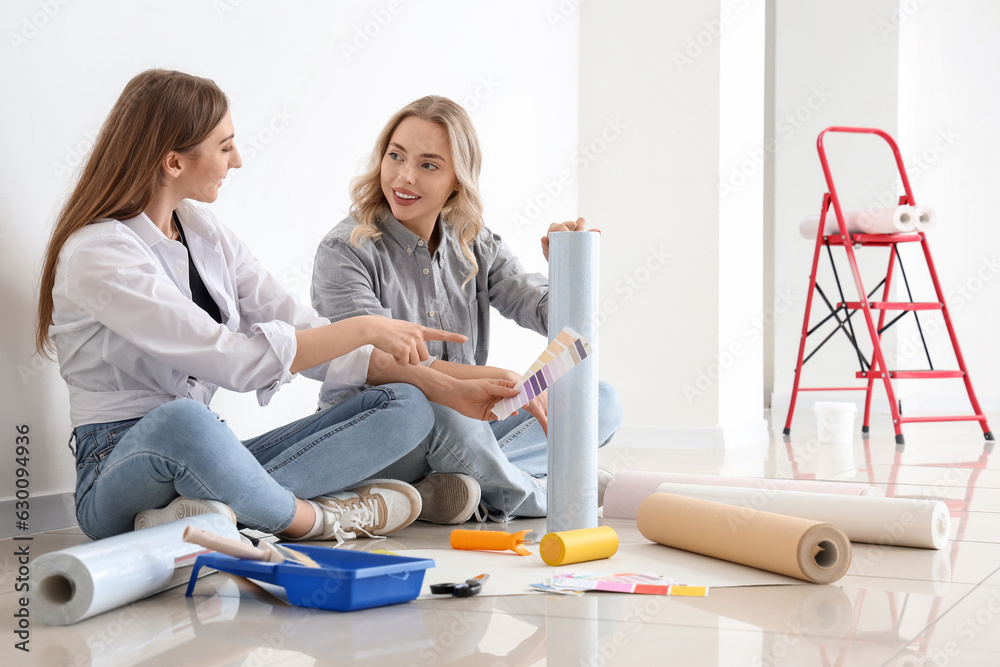 Young women with wallpaper roll and paint color palettes at home