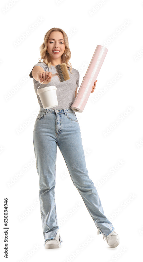 Young woman with wallpaper roll, brush and glue on white background