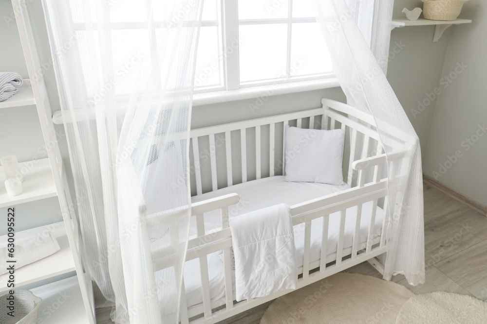 Interior of stylish childrens bedroom with crib and shelving unit