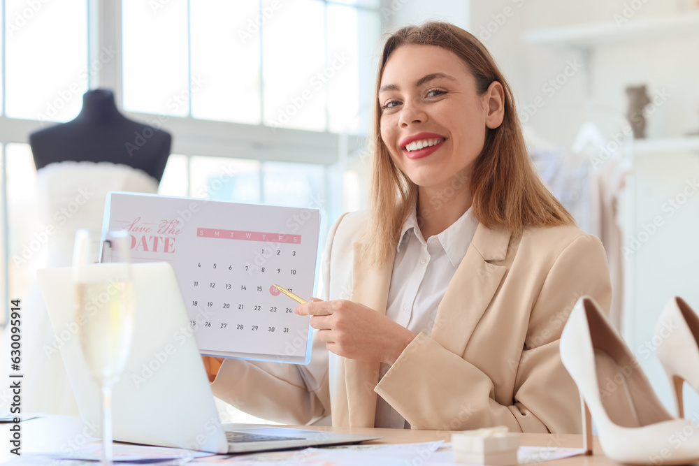 Female wedding planner working with Save the Date Announcement at table in office