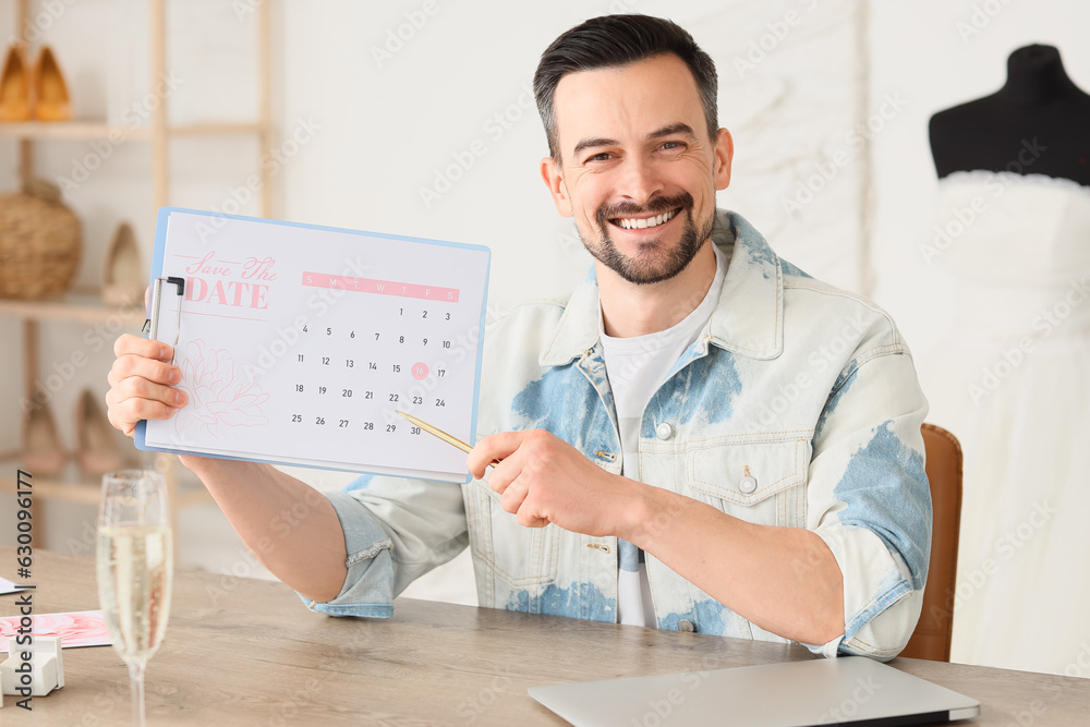 Male wedding planner with Save the Date announcement in office