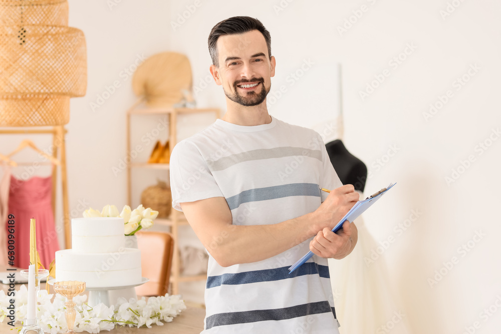 Male wedding planner with clipboard in office