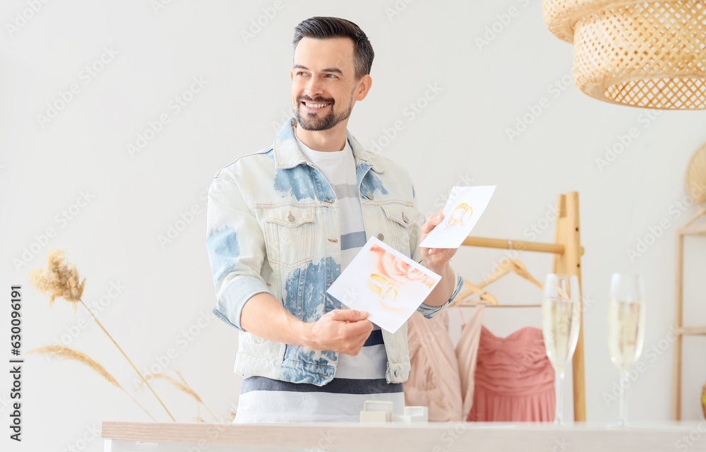 Male wedding planner with pictures of rings in office