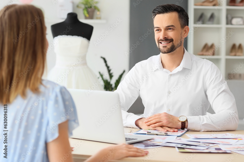 Male wedding planner working with client in office