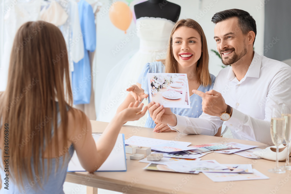 Young couple with pictures planning their wedding in office