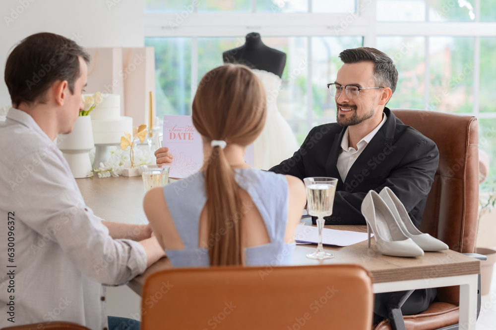 Male wedding planner working with couple in office