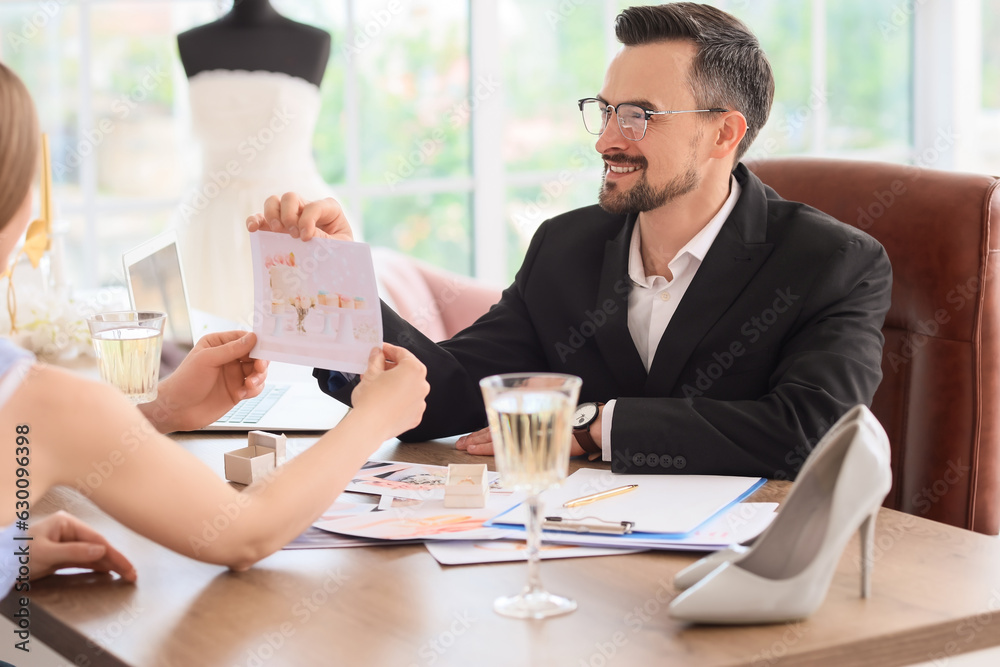 Male wedding planner working with couple in office