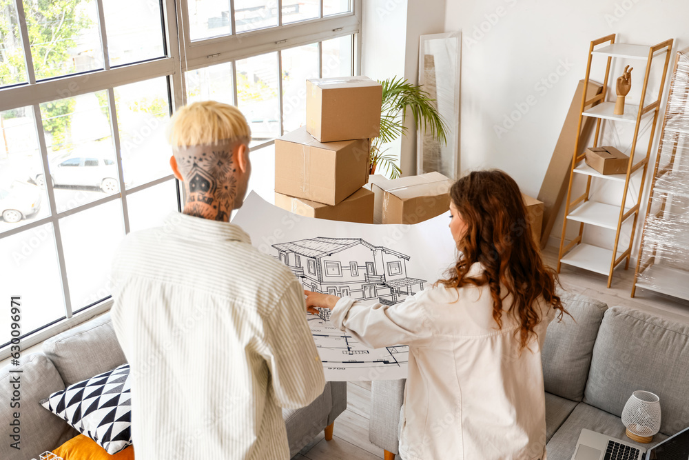 Young couple with house plan in room on moving day, back view