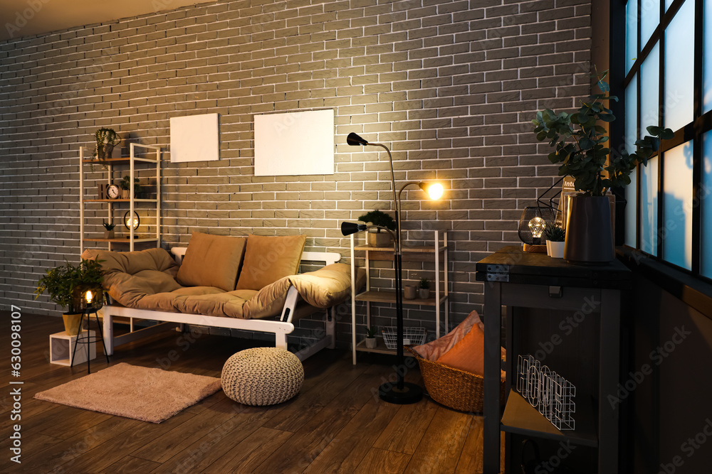 Interior of dark living room with couch, shelving units and glowing lamps