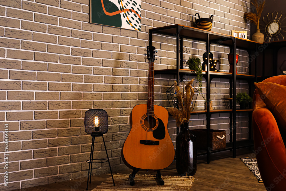 Glowing lamp with guitar in dark living room