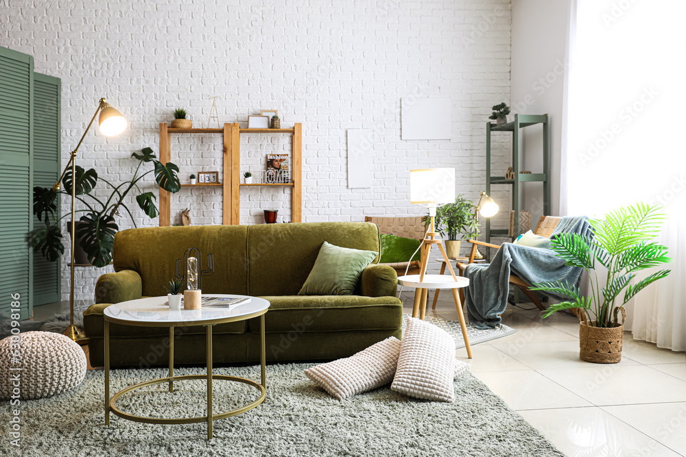 Interior of living room with glowing lamps, sofa and houseplants