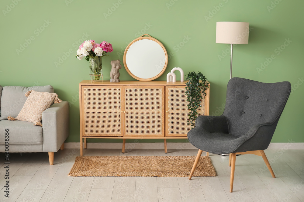 Armchair with dresser, couch and lamp near green wall