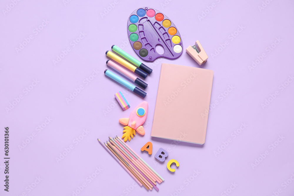 Rocket made of plasticine with different stationery and wooden letters on lilac background