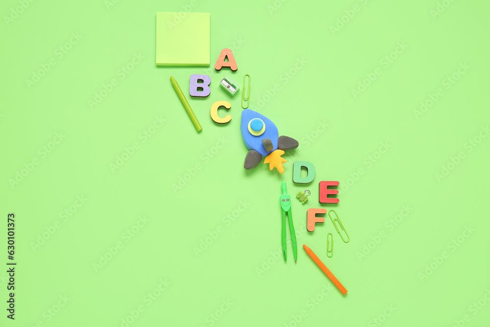 Rocket made of plasticine with wooden letters and stationery on green background