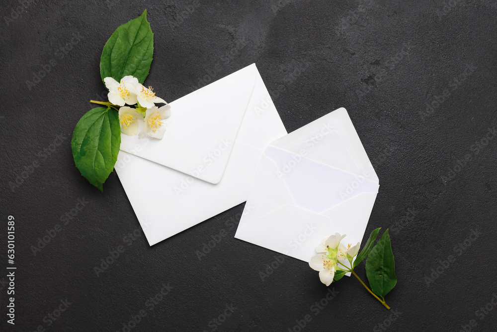 Envelopes with blank card and blooming jasmine branches on dark background