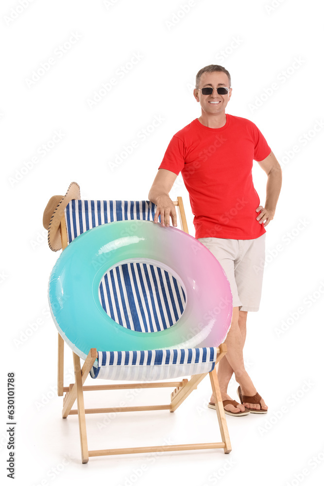 Mature man and deck chair with swim ring on white background