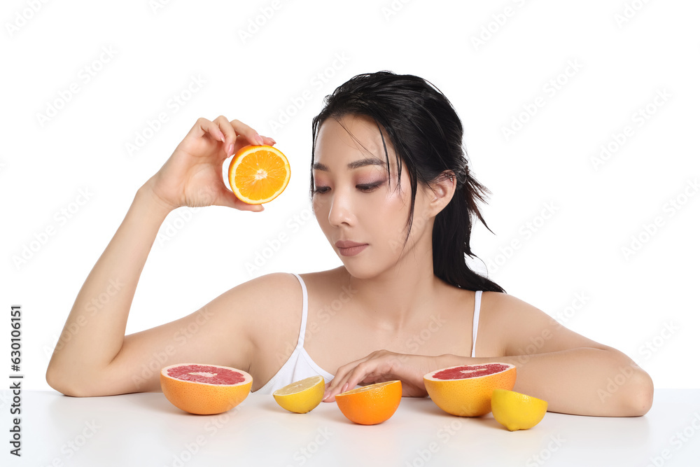 Beautiful young Asian woman with citrus fruits on white background