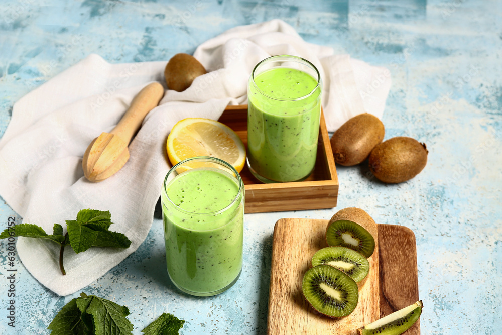 Glasses of fresh kiwi smoothie with mint and lemon on light blue background