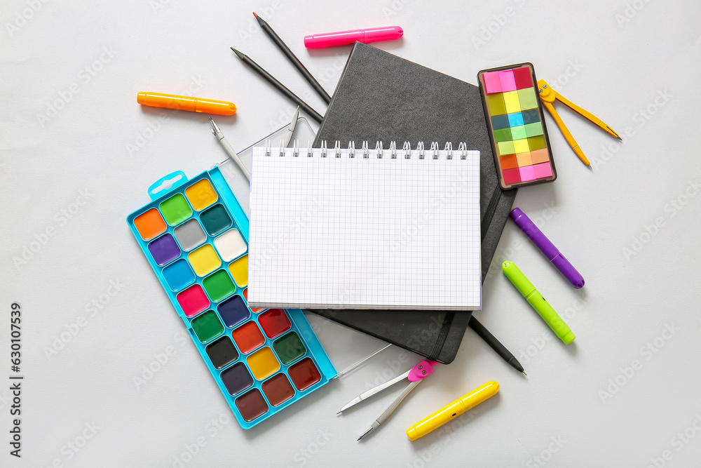 Composition with blank notebook and different school stationery on light background