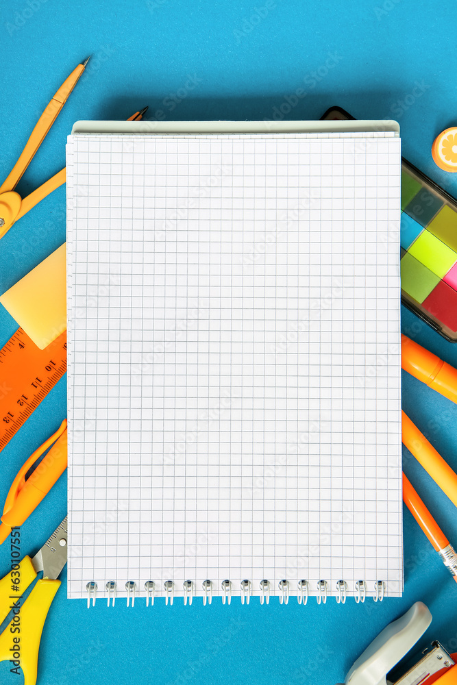 Composition with blank notebook and different school stationery on blue background