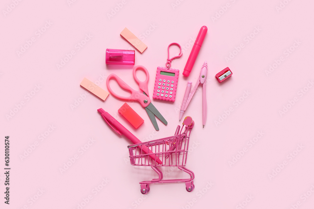 Shopping cart with different school stationery on pink background